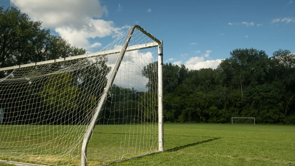 Fotboll i gräset framför ett mål